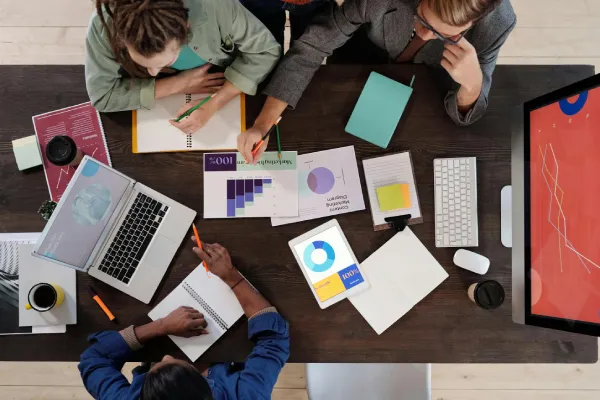 Several people sitting around a desk with documents and charts